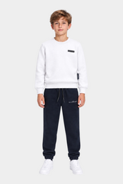 Ragazzo indossa completo sportivo Follower SRL con felpa bianca e pantaloni della tuta blu scuro con logo RICHMOND