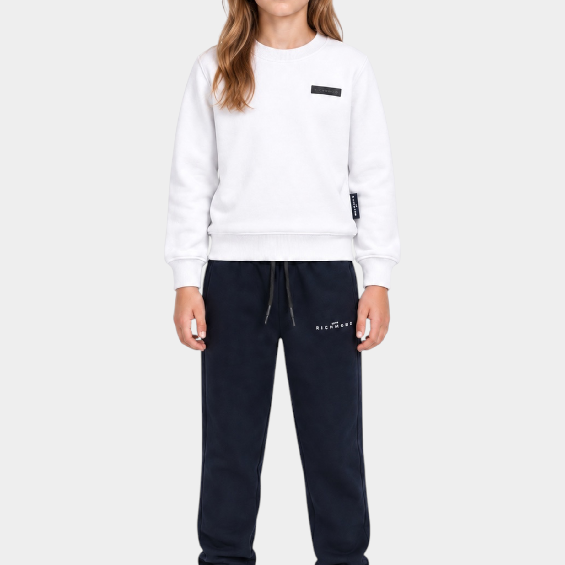 Ragazza indossa completo sportivo Follower SRL con felpa bianca girocollo e pantaloni della tuta blu scuro