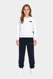 Ragazza indossa completo sportivo Follower SRL con felpa bianca girocollo e pantaloni della tuta blu scuro