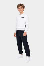 Ragazzo indossa completo sportivo Follower SRL con felpa bianca e pantaloni jogger blu scuro con logo RICHMOND
