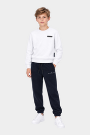 Ragazzo indossa completo sportivo Follower SRL con felpa bianca e pantaloni neri con logo RICHMOND