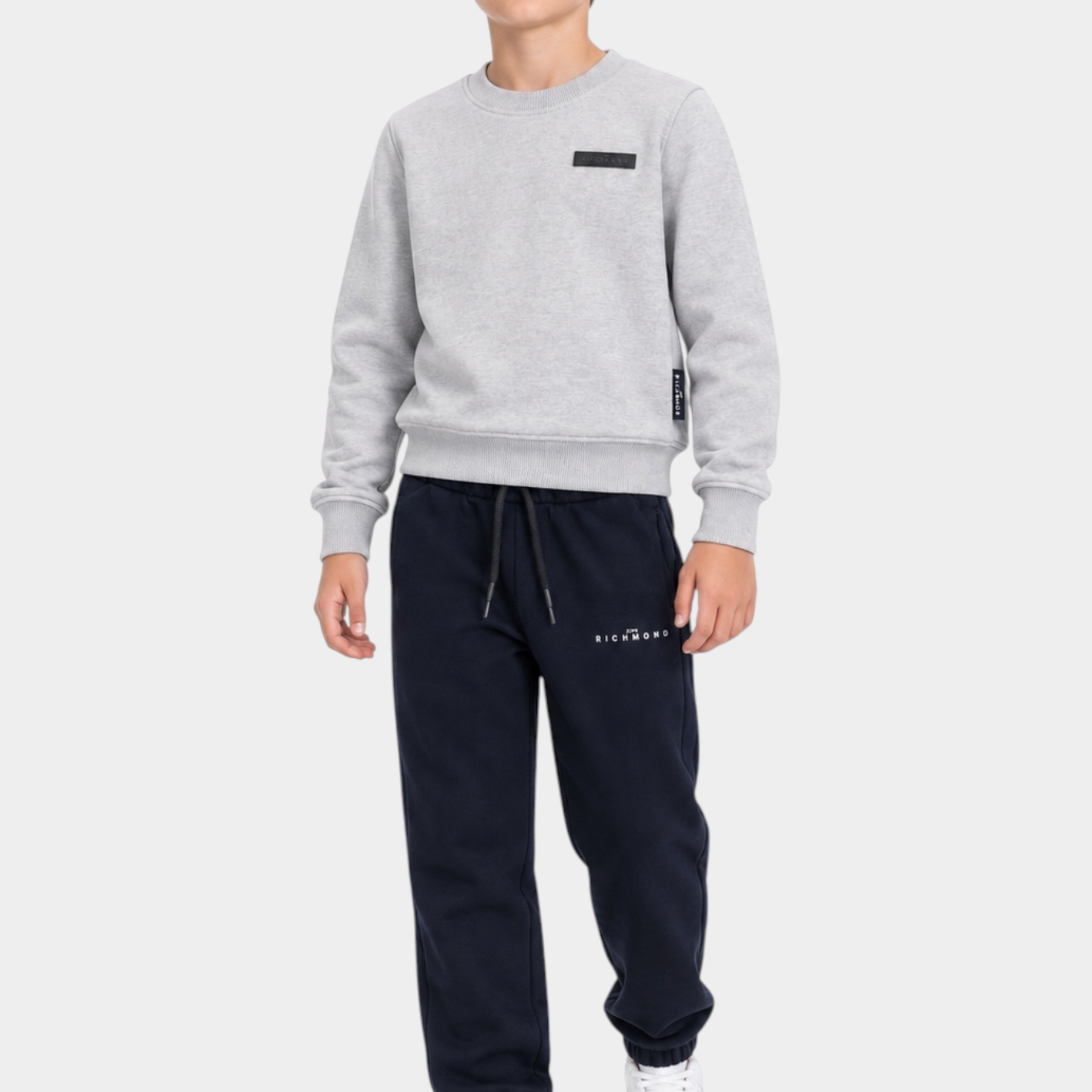 Ragazzo indossa completo sportivo Follower SRL con felpa grigia girocollo e pantaloni jogger blu scuro