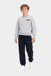 Ragazzo indossa completo sportivo Follower SRL con felpa grigia girocollo e pantaloni jogger blu scuro