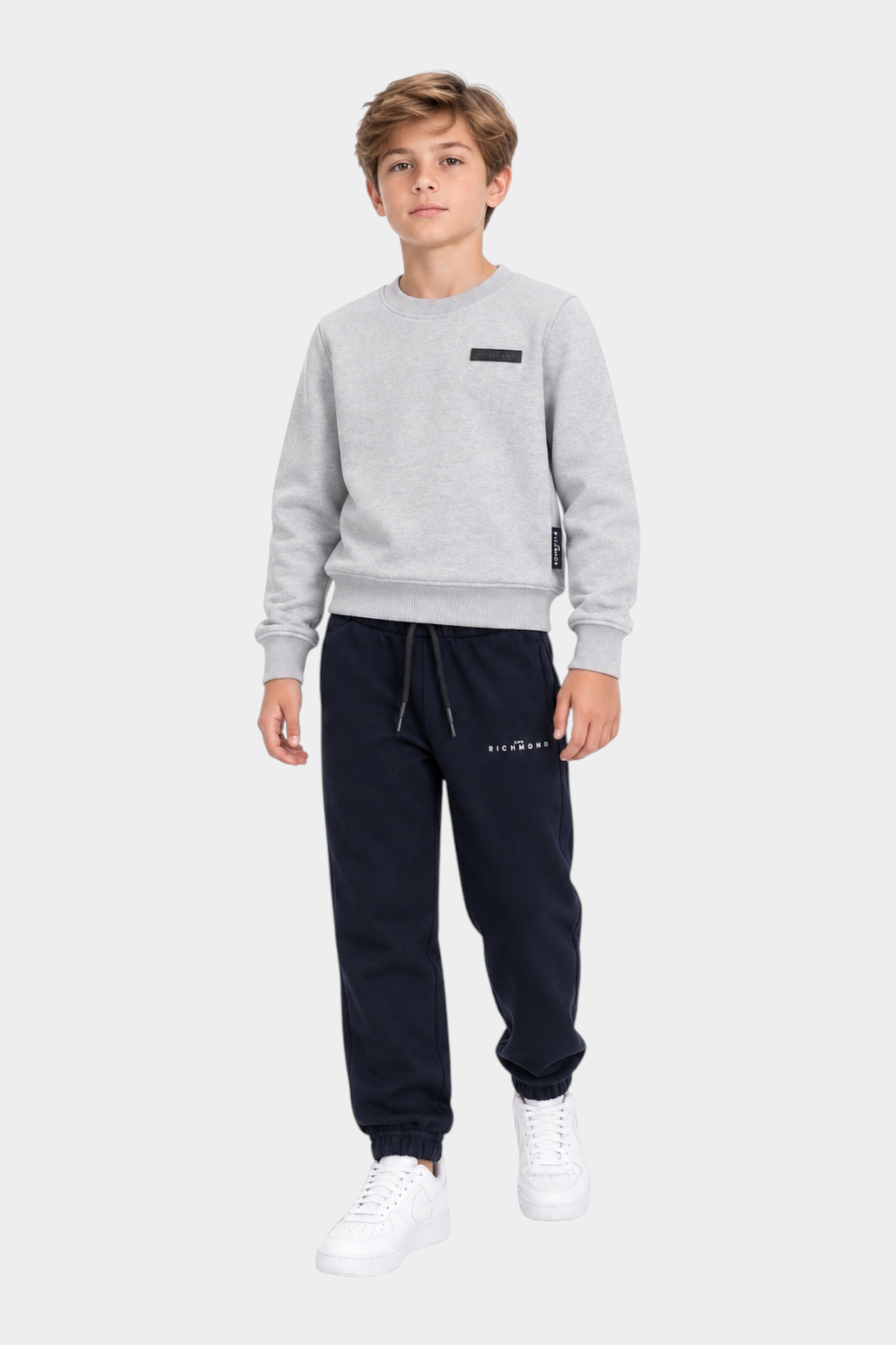 Ragazzo indossa completo sportivo Follower SRL con felpa grigia girocollo e pantaloni jogger blu scuro