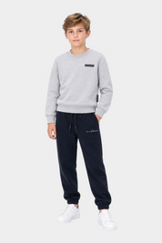 Ragazzo indossa un completo sportivo Follower SRL con felpa grigia a girocollo e pantaloni della tuta blu navy