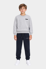 Ragazzo indossa completo sportivo Follower SRL con felpa grigia e pantaloni jogger blu navy con logo RICHMOND