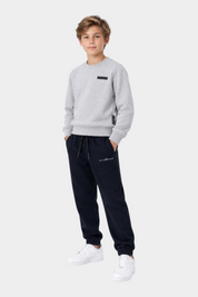 Ragazzo indossa completo sportivo Follower SRL con felpa grigia girocollo e pantaloni jogger blu scuro