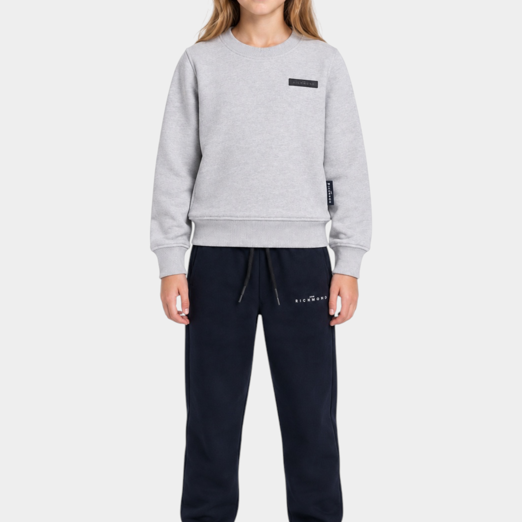 Ragazza indossa completo sportivo Follower SRL con felpa grigia girocollo e pantaloni jogger neri con logo RICHMOND