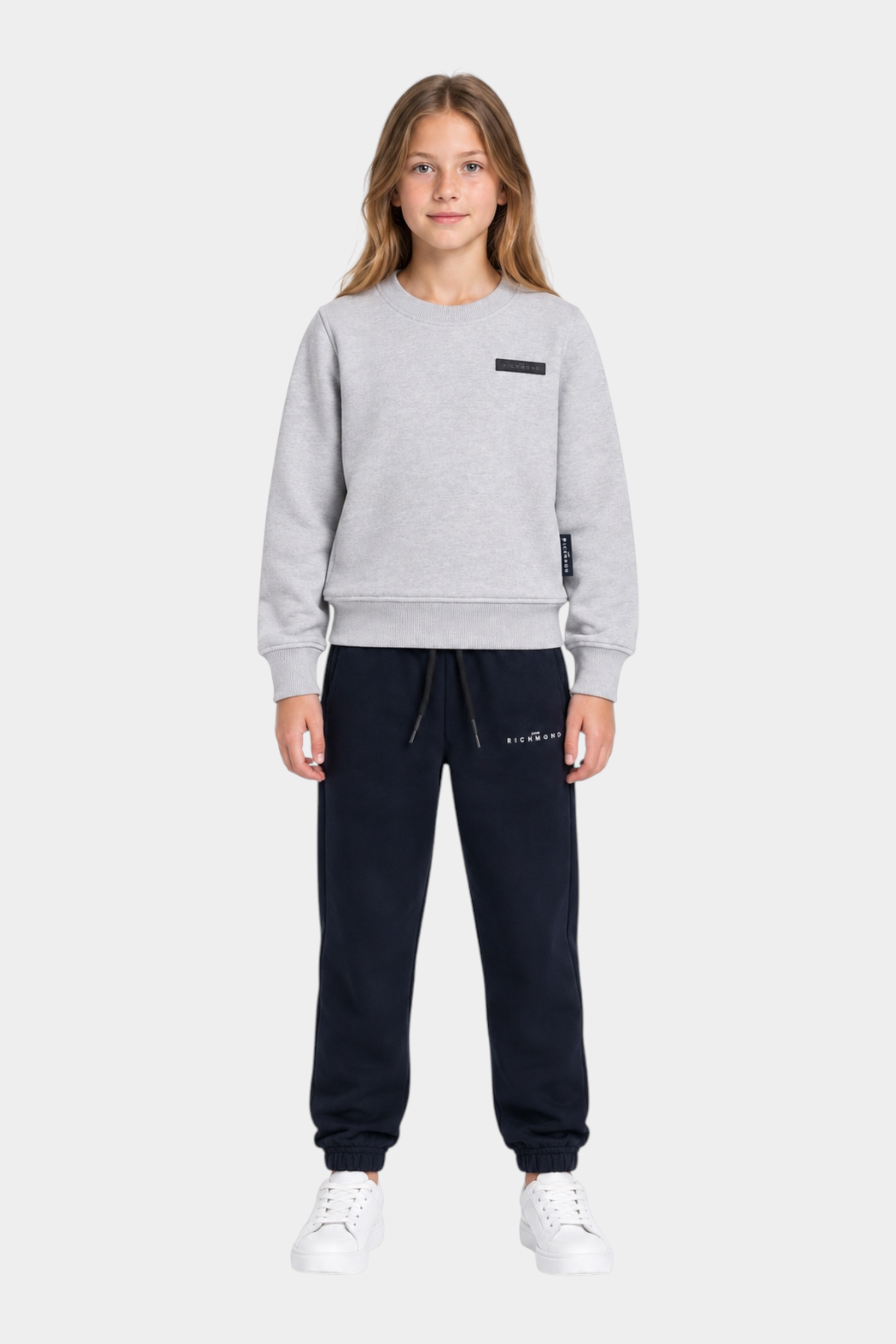 Ragazza indossa completo sportivo Follower SRL con felpa grigia girocollo e pantaloni jogger neri con logo RICHMOND