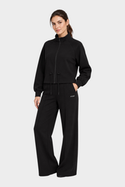 Modella indossa un completo sportivo nero Follower SRL composto da giacca con zip e pantaloni jogger a gamba larga
