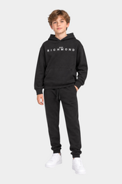 Ragazzo indossa un completo sportivo nero Follower SRL con felpa con cappuccio e logo John Richmond bianco