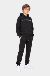 Ragazzo indossa un completo sportivo nero Follower SRL con felpa con cappuccio e logo RICHMOND e pantaloni jogger