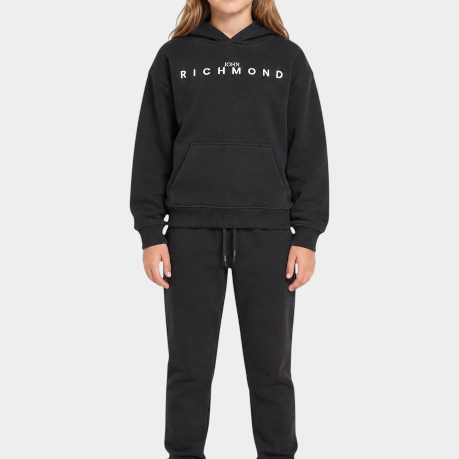 Ragazza che indossa un completo sportivo nero Follower SRL con felpa con cappuccio e logo RICHMOND bianco