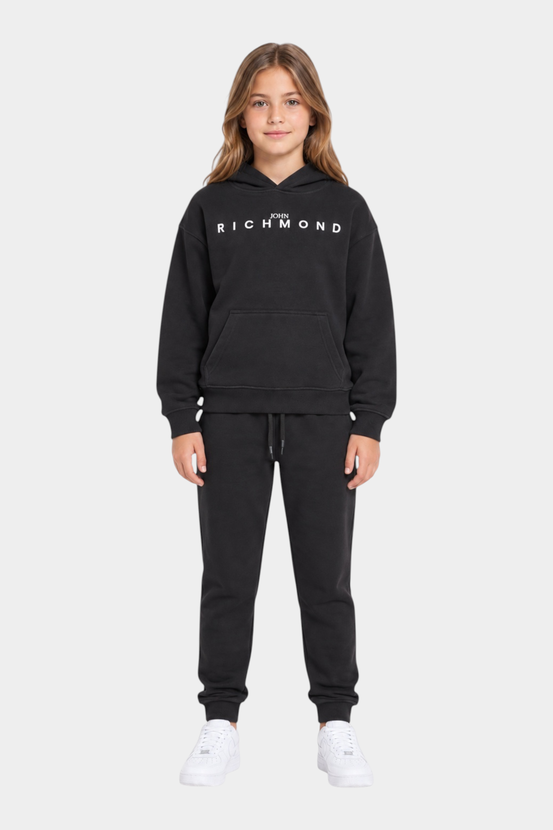 Ragazza che indossa un completo sportivo nero Follower SRL con felpa con cappuccio e logo RICHMOND bianco