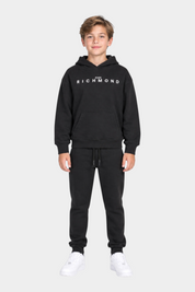 Ragazzo indossa un completo sportivo nero Follower SRL con felpa con cappuccio e logo John Richmond bianco