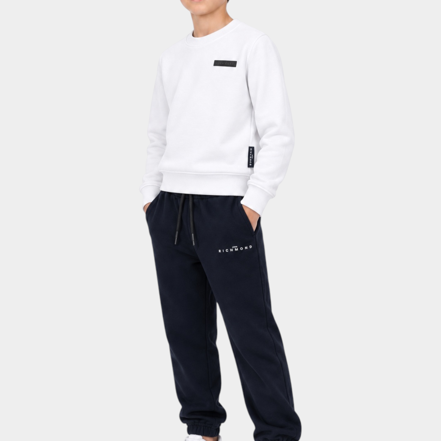 Ragazzo indossa un completo sportivo Follower SRL con felpa bianca e pantaloni della tuta blu scuro