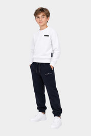 Ragazzo indossa un completo sportivo Follower SRL con felpa bianca e pantaloni della tuta blu scuro