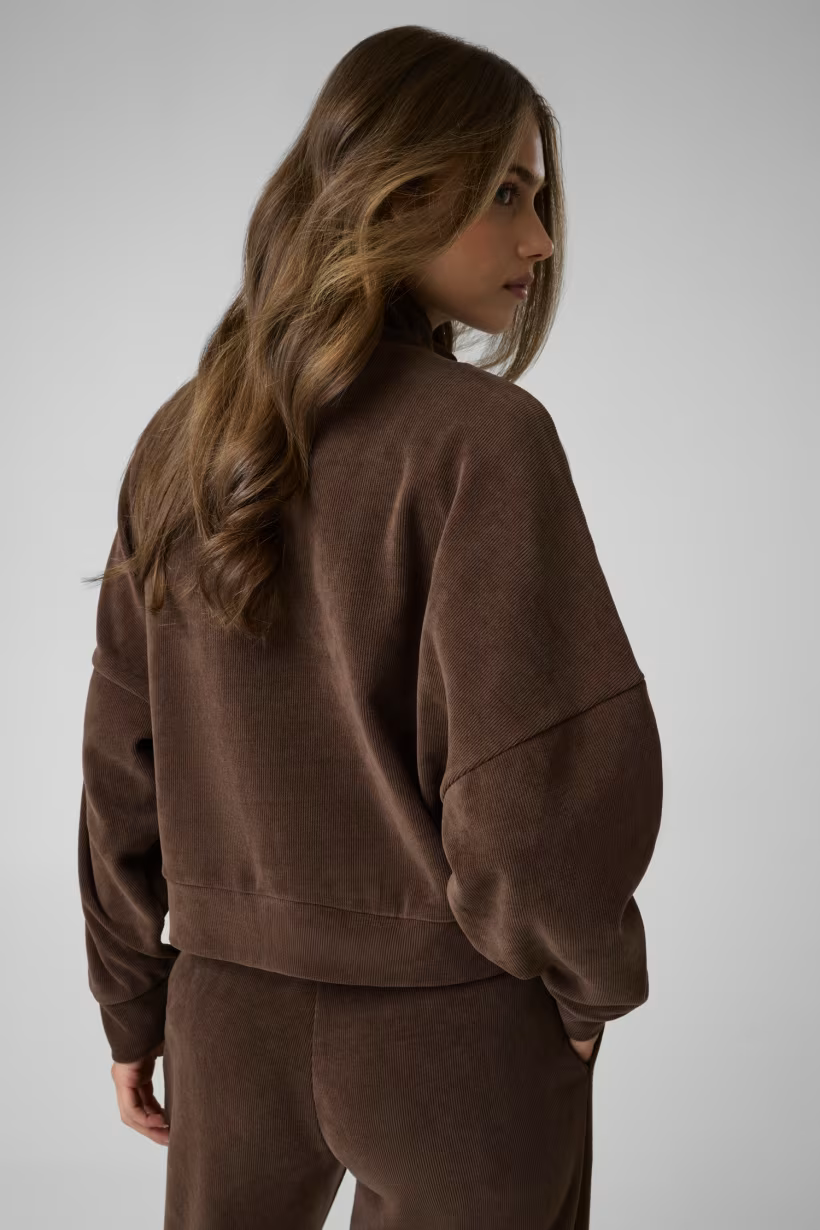 Felpa a coste marrone GUESS indossata da una modella, vista posteriore, design casual con spalle scese Follower SRL