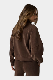 Felpa a coste marrone GUESS indossata da una modella, vista posteriore, design casual con spalle scese Follower SRL