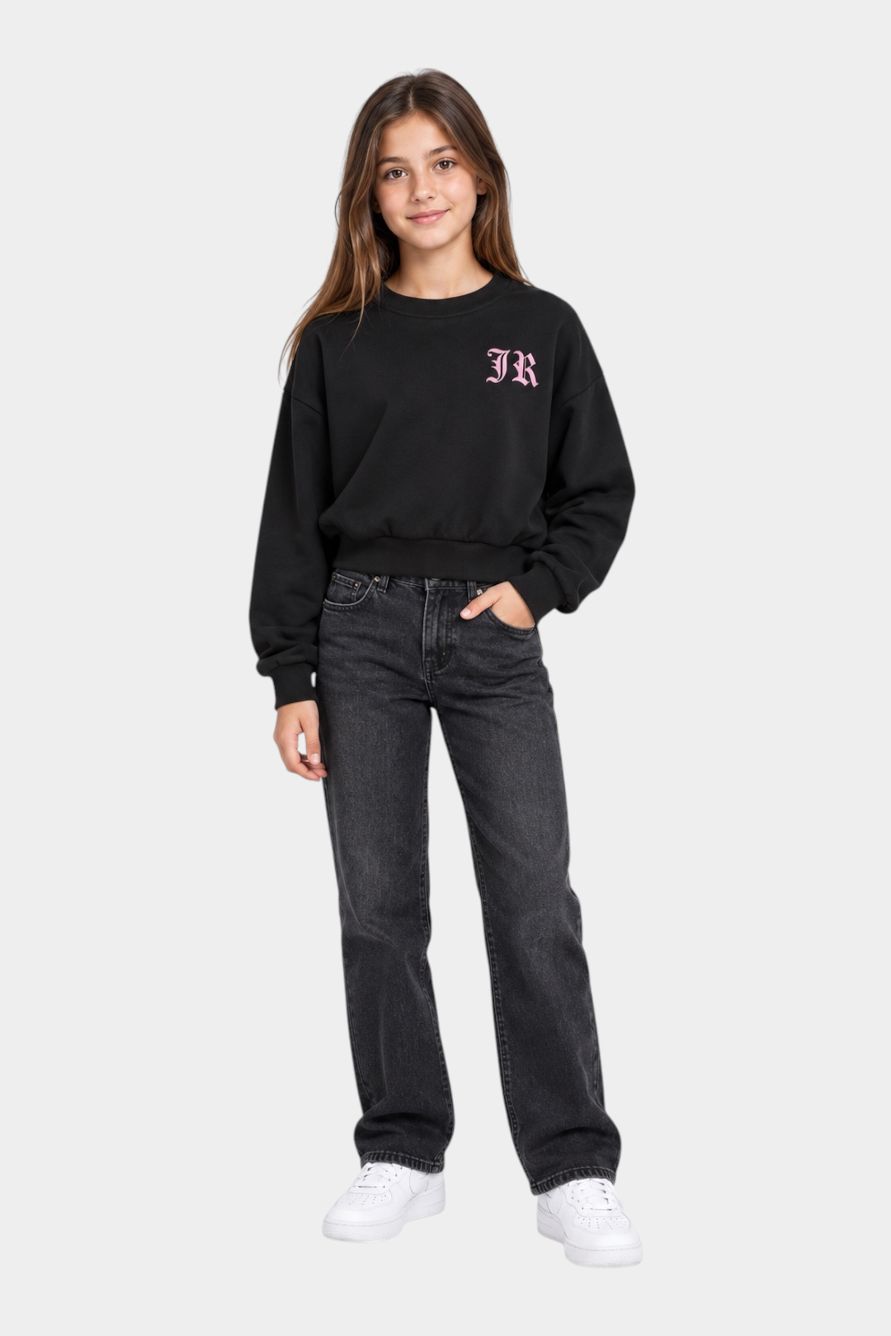Ragazza indossa felpa girocollo nera Follower SRL con logo rosa, abbinata a jeans scuri e scarpe bianche