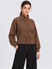 Felpa full zip marrone da donna GUESS indossata da una modella, con colletto alto e coulisse in vita Follower SRL