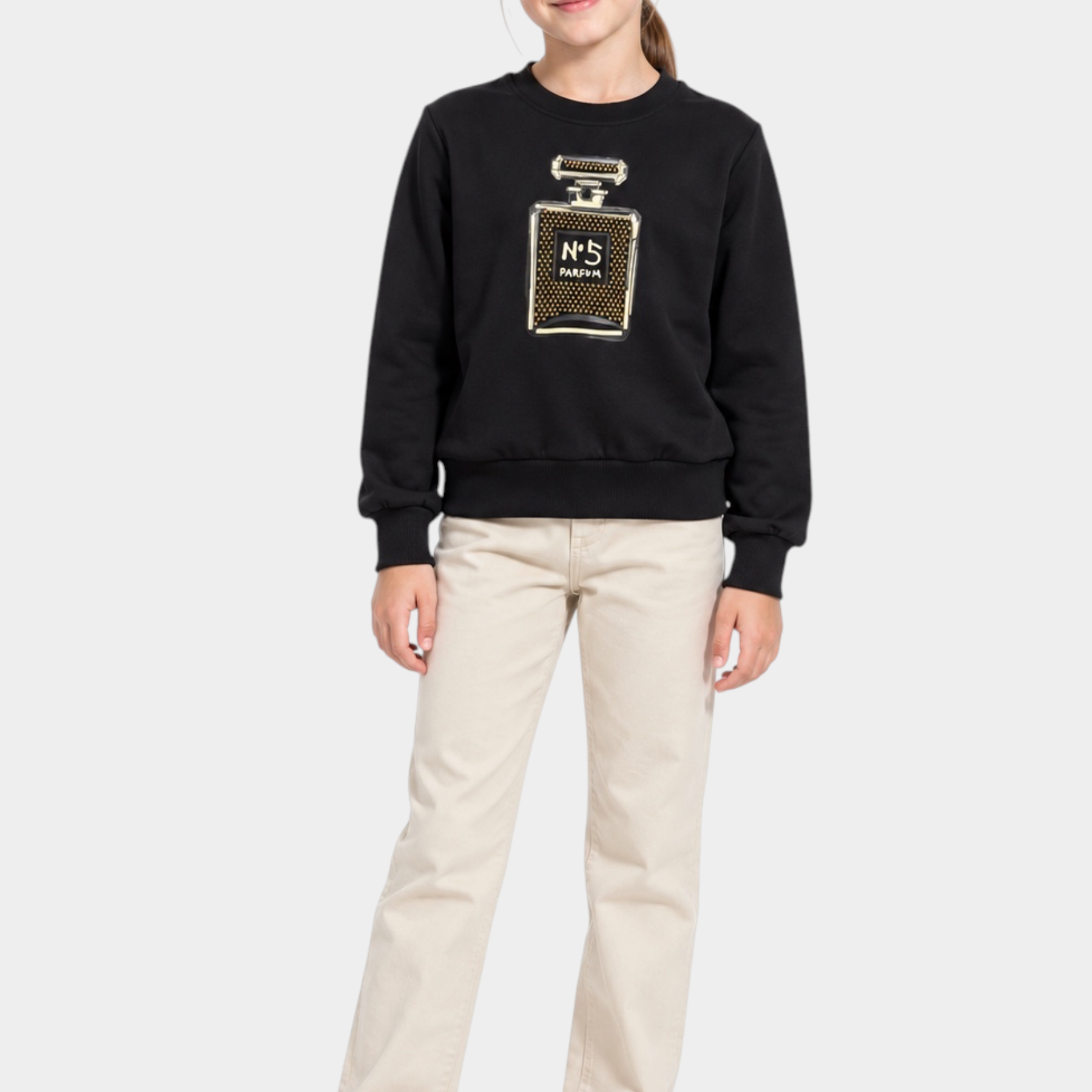 Bambina indossa felpa nera Follower SRL con decorazione gioiello a forma di profumo e strass, abbinata a pantaloni beige
