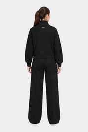 Donna che indossa una felpa full zip nera Follower SRL con logo GUESS sul retro e pantaloni abbinati