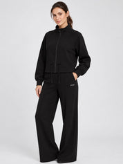 Modella indossa felpa full zip nera GUESS con coulisse in vita e pantaloni coordinati a gamba larga