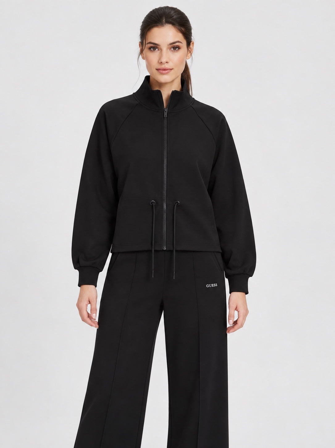 Modella indossa felpa full zip nera Follower SRL con coulisse in vita e collo alto, abbinata a pantaloni neri