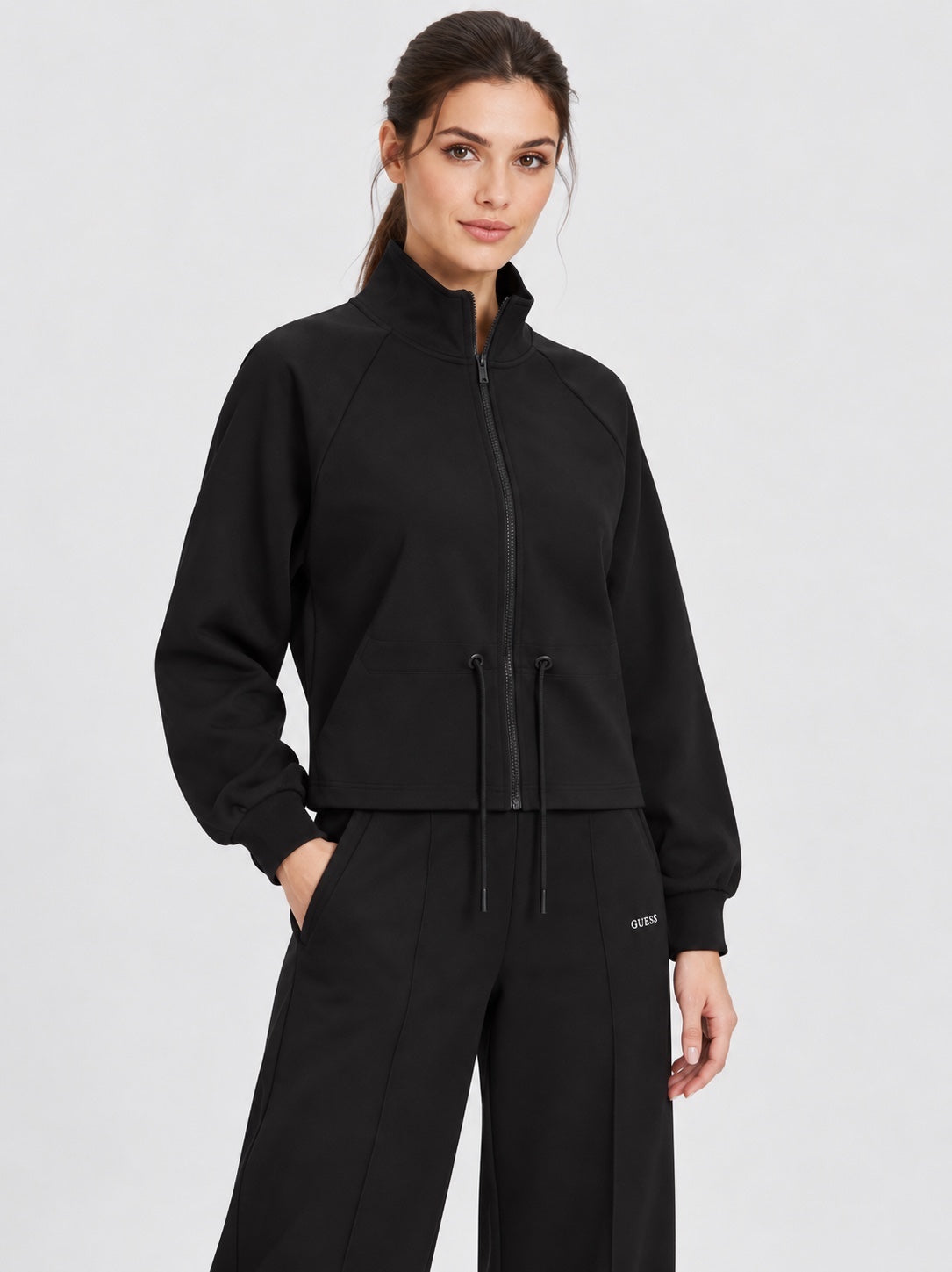 Modella indossa felpa full zip nera Follower SRL con collo alto e coulisse in vita, stile sportivo ed elegante