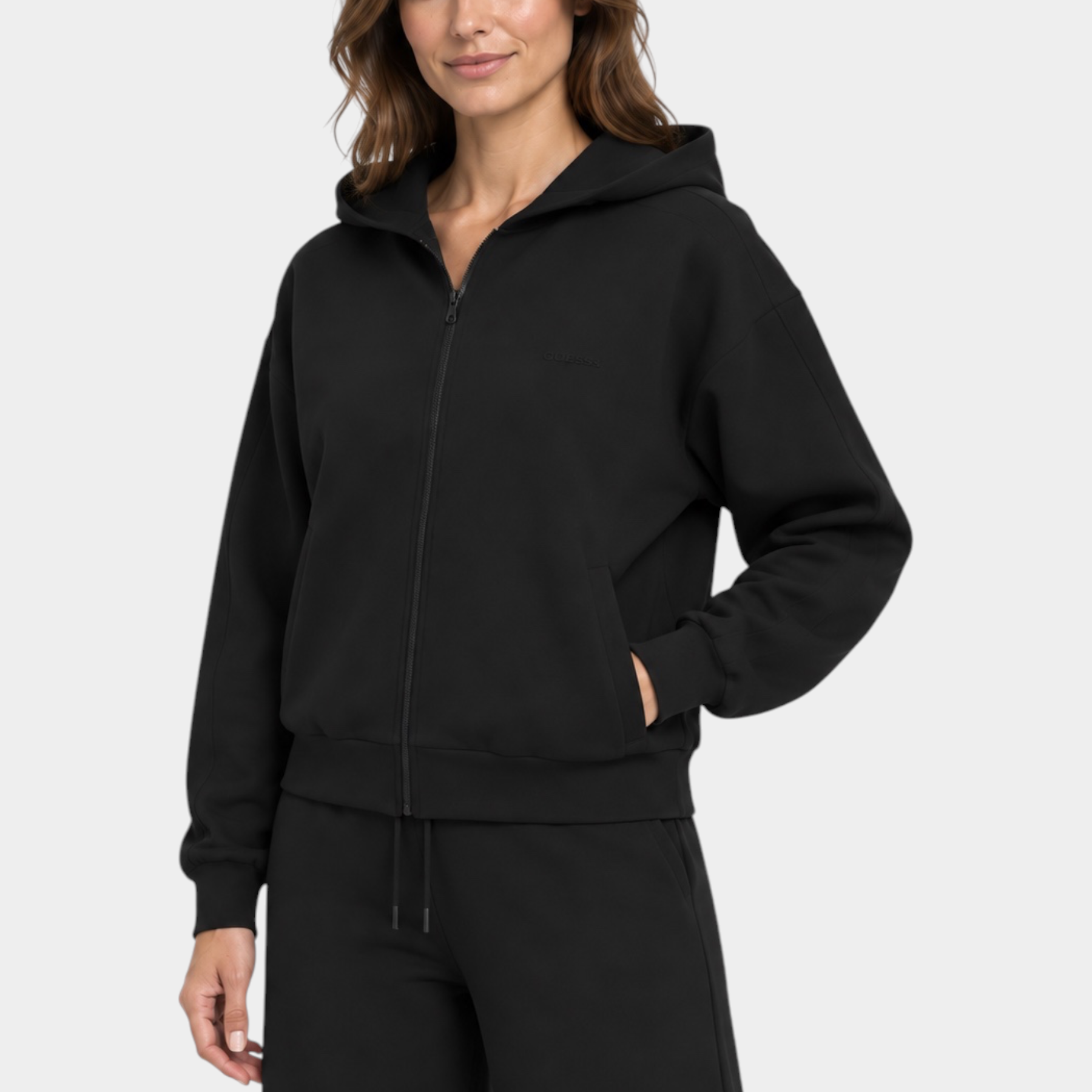 Modella indossa felpa con cappuccio e zip intera nera GUESS di Follower SRL, design minimalista e vestibilità comoda