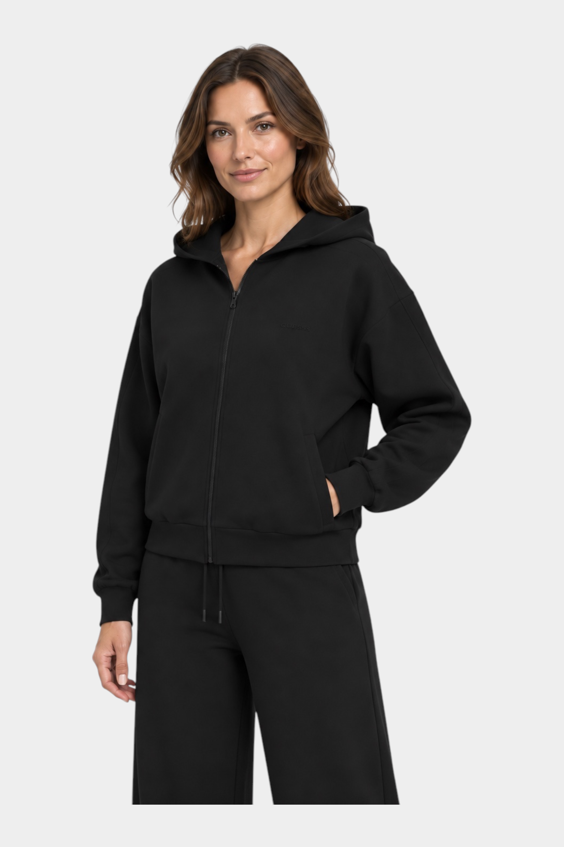 Modella indossa felpa con cappuccio e zip intera nera GUESS di Follower SRL, design minimalista e vestibilità comoda