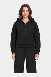 Modella indossa una felpa con cappuccio e zip intera nera GUESS, dal design minimalista e vestibilità confortevole.