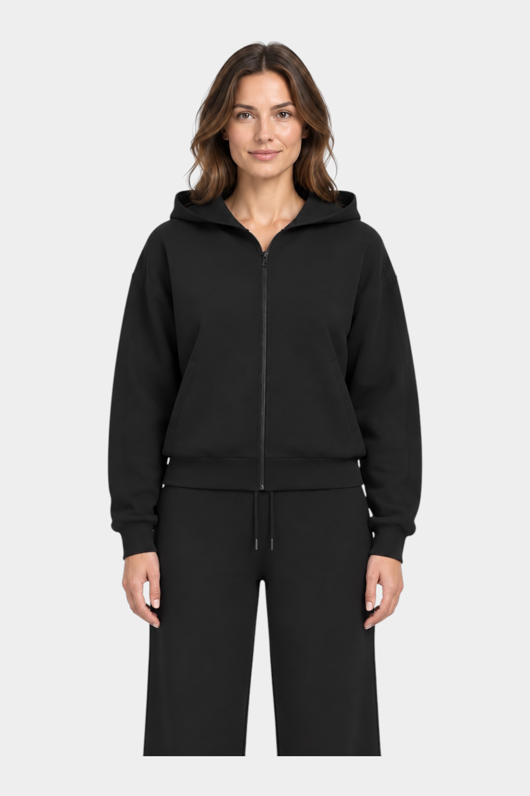 Modella indossa una felpa con cappuccio e zip intera nera GUESS, dal design minimalista e vestibilità confortevole.