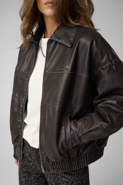 Giacca bomber Follower SRL in similpelle marrone con zip frontale e cuciture a vista indossata da una modella