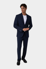 Modello indossa giacca monopetto blu GUESS con t-shirt bianca e pantaloni abbinati, collezione Follower SRL