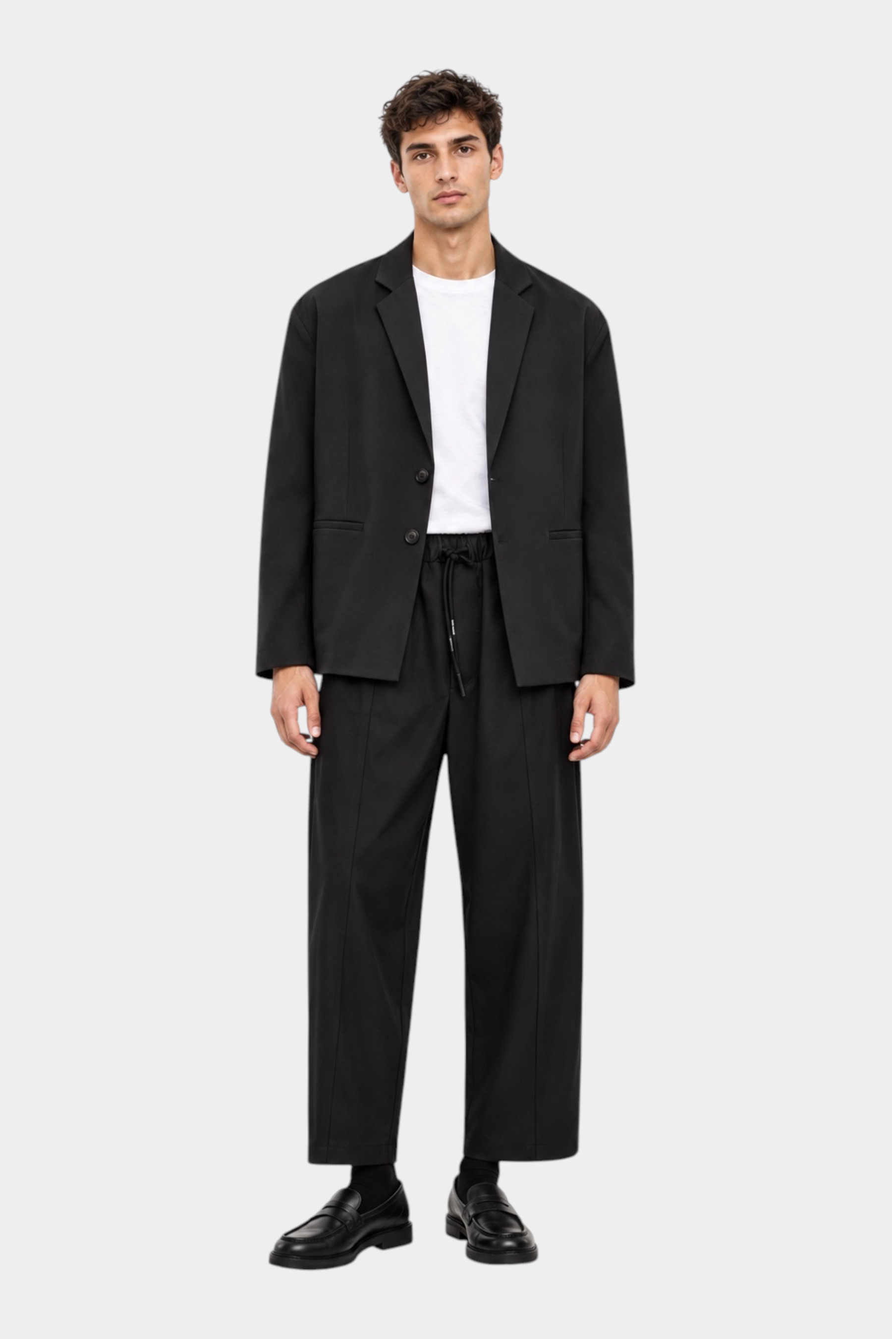 Modello indossa giacca nera IMPERIAL regular-fit con due bottoni su t-shirt bianca e pantaloni coordinati