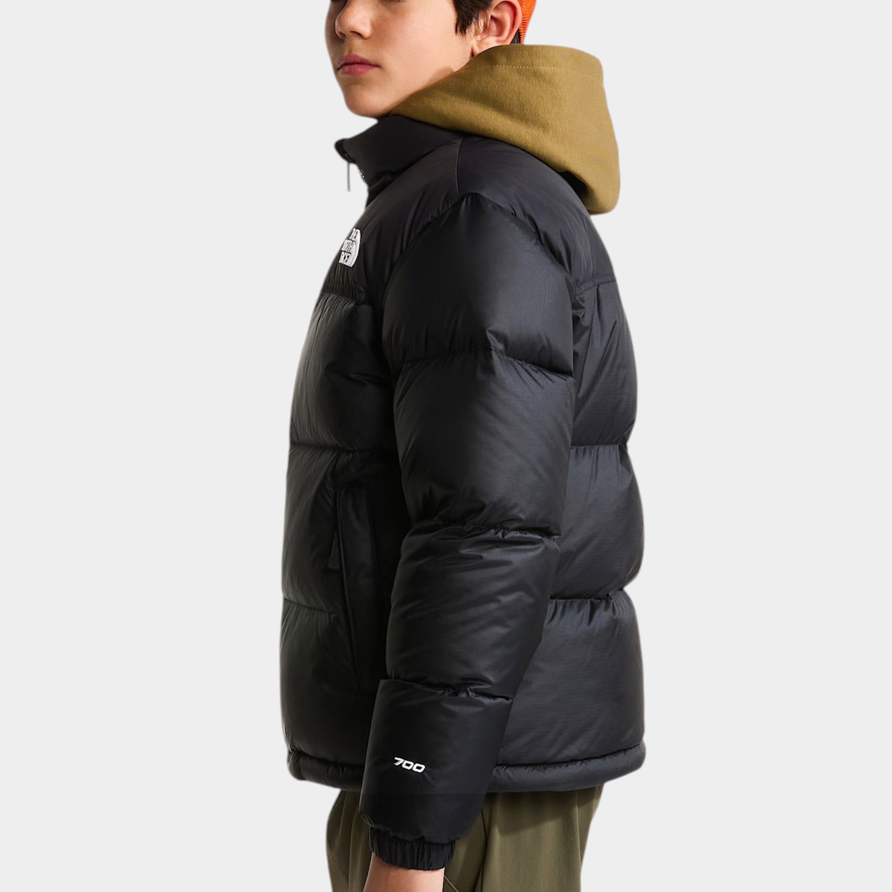Ragazzo indossa giacca nera 1996 Retro Nuptse Follower SRL con cappuccio color oliva e cappellino arancione