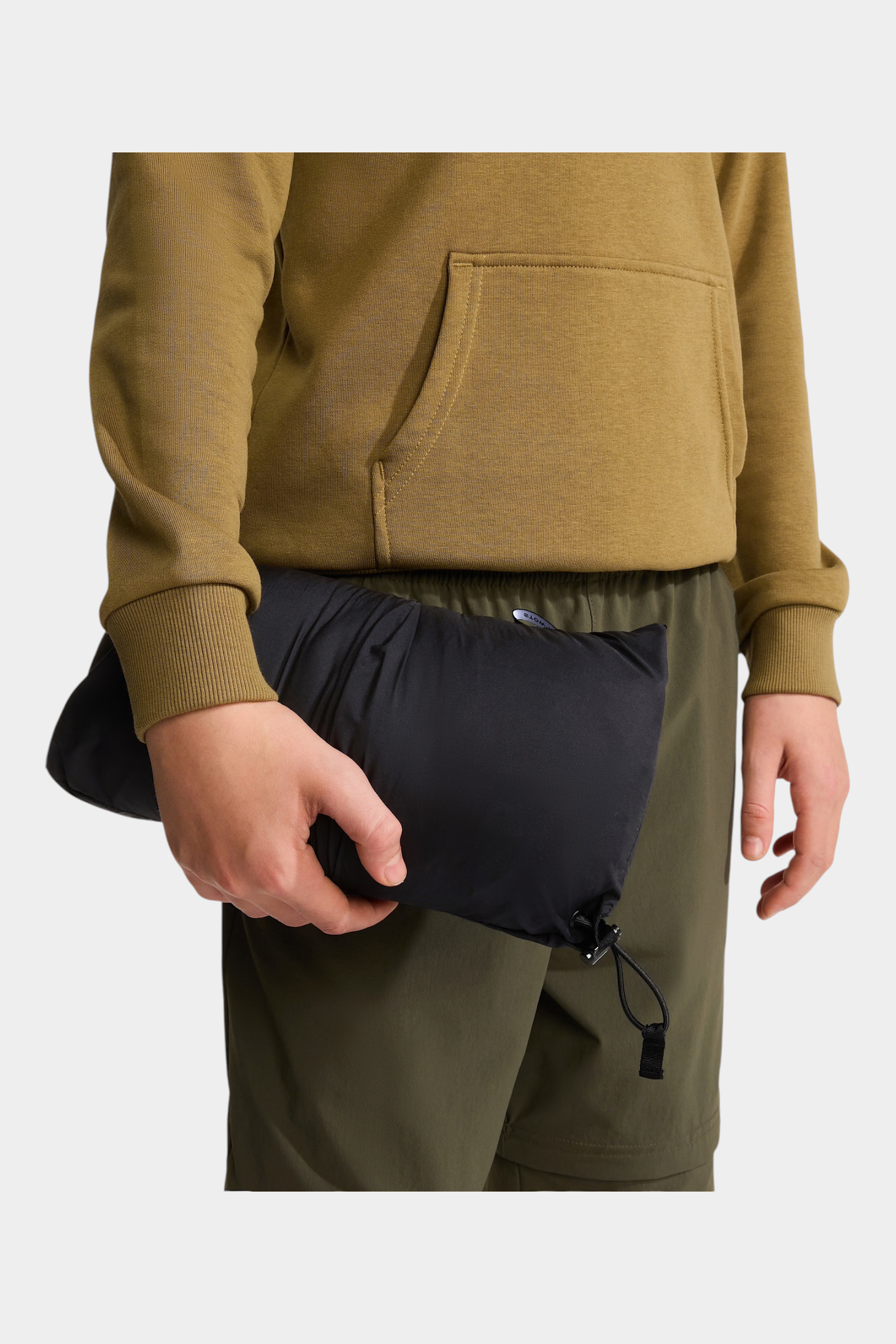 Follower SRL Giacca 1996 Retro Nuptse nera ripiegata tenuta in mano da un ragazzo con felpa color oliva