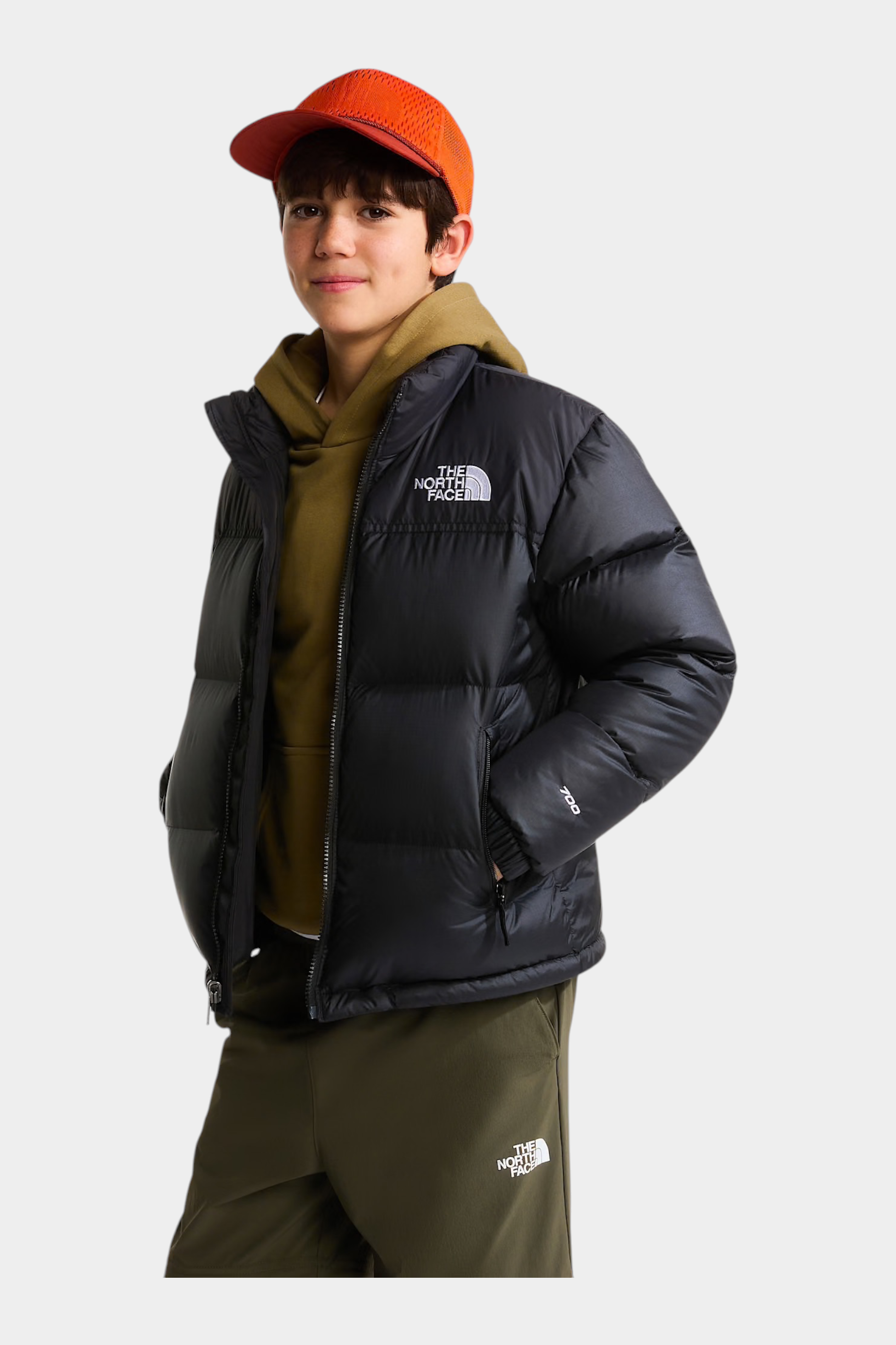 Ragazzo indossa giacca nera 1996 Retro Nuptse Follower SRL con cappellino arancione e felpa verde oliva