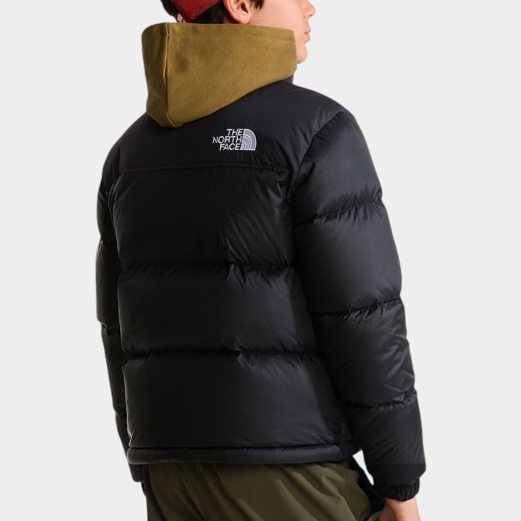 Ragazzo indossa giacca imbottita nera 1996 Retro Nuptse Follower SRL con cappuccio verde e cappellino arancione