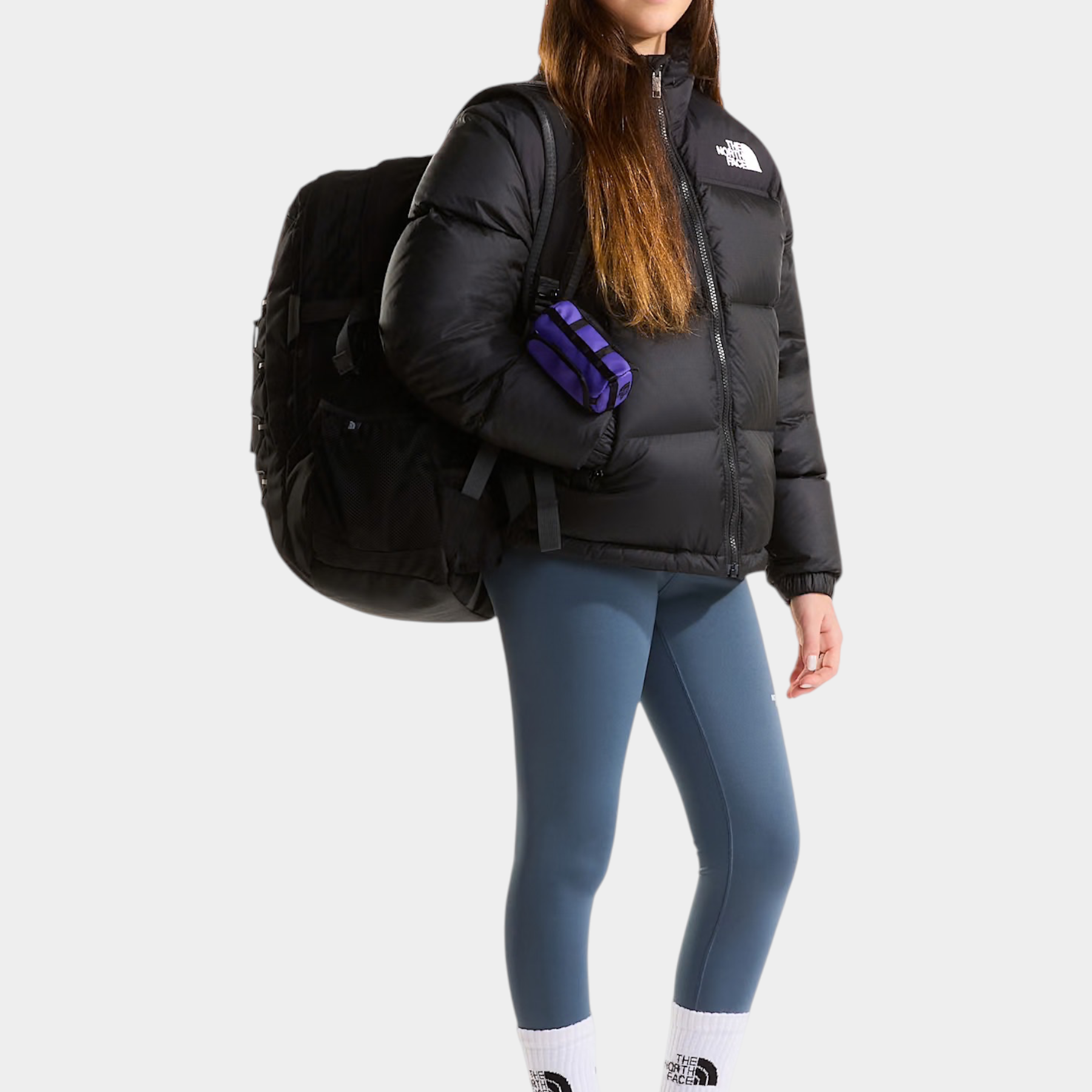 Ragazza indossa giacca nera 1996 Retro Nuptse Follower SRL con zaino, leggings blu e berretto in stile invernale