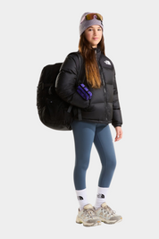 Ragazza indossa giacca nera 1996 Retro Nuptse Follower SRL con zaino, leggings blu e berretto in stile invernale