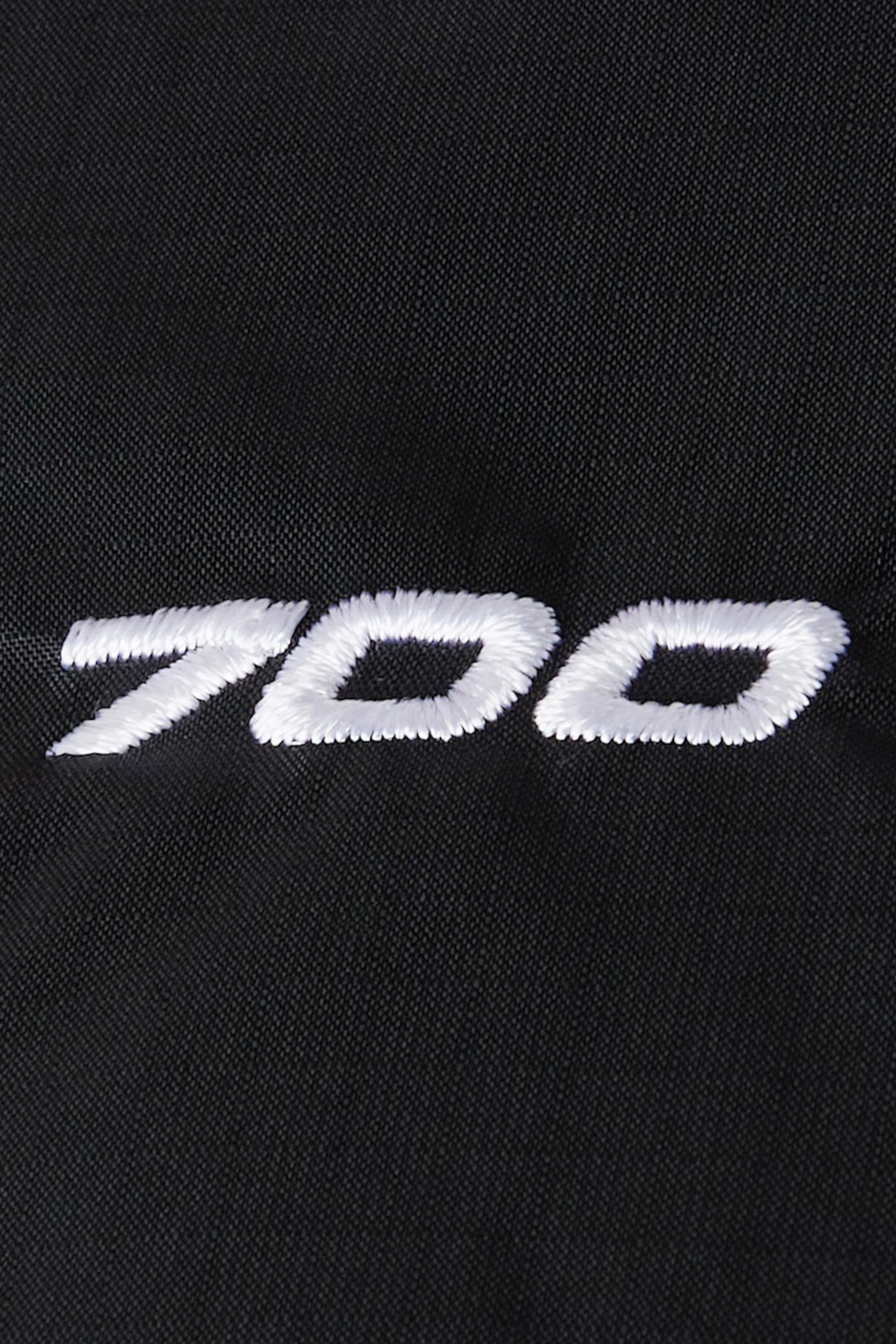 Dettaglio del ricamo bianco 700 su tessuto nero della giacca Follower SRL 1996 Retro Nuptse