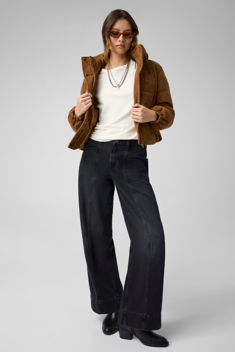 Modella indossa giacca imbottita corta in pelle scamosciata marrone GUESS con jeans neri a gamba larga Follower SRL