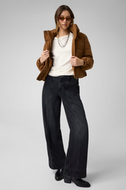 Modella indossa giacca imbottita corta in pelle scamosciata marrone GUESS con jeans neri a gamba larga Follower SRL