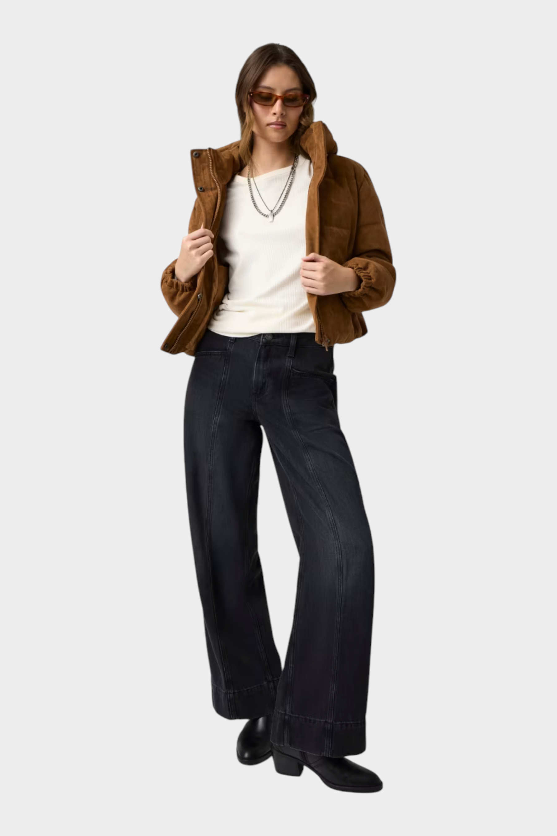 Modella indossa giacca imbottita corta in pelle scamosciata marrone GUESS con jeans neri a gamba larga Follower SRL