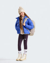 Ragazza indossa giacca in piumino blu con cappuccio THE NORTH FACE di Follower SRL con zaino e leggings viola