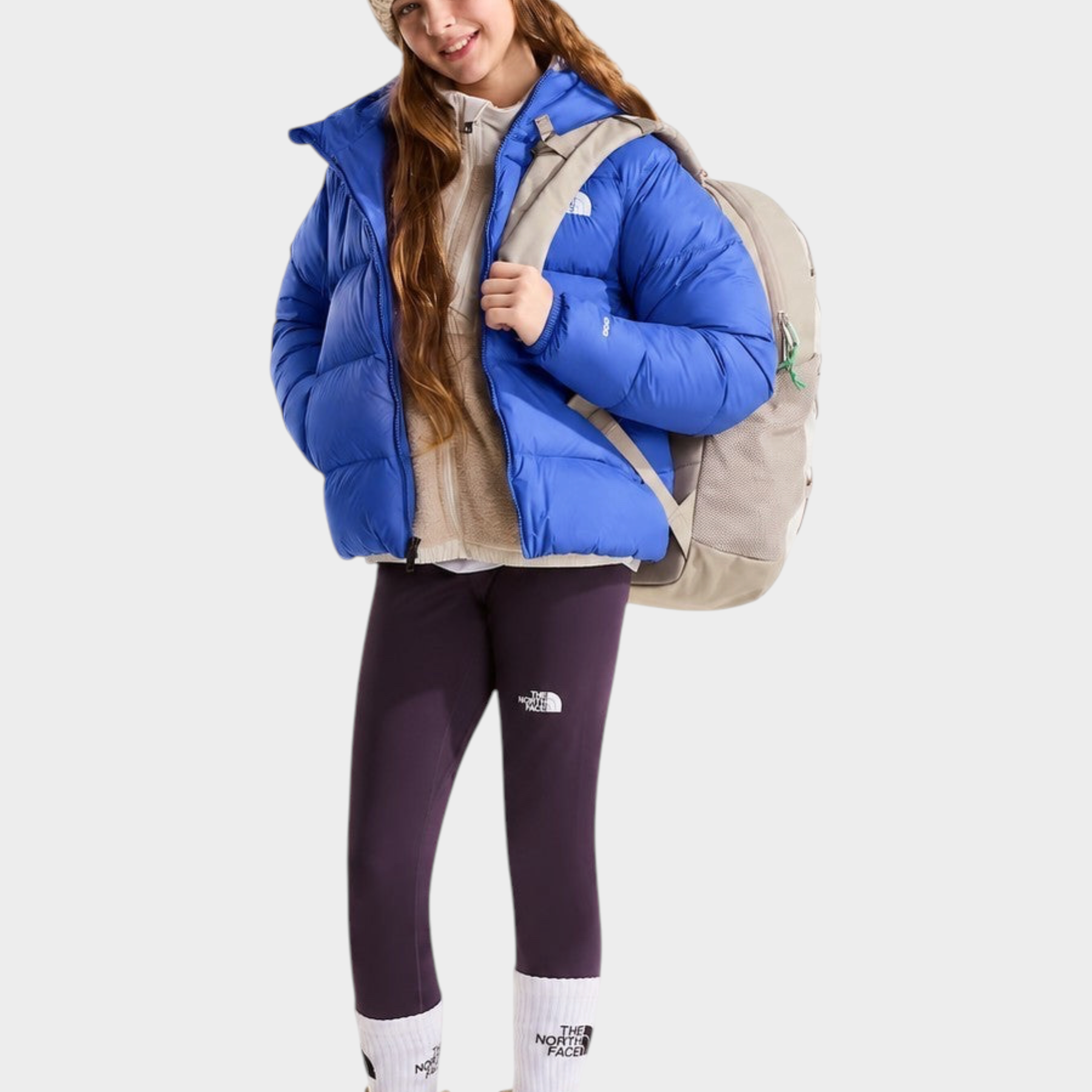 Ragazza indossa giacca in piumino blu con cappuccio THE NORTH FACE di Follower SRL con zaino e leggings viola