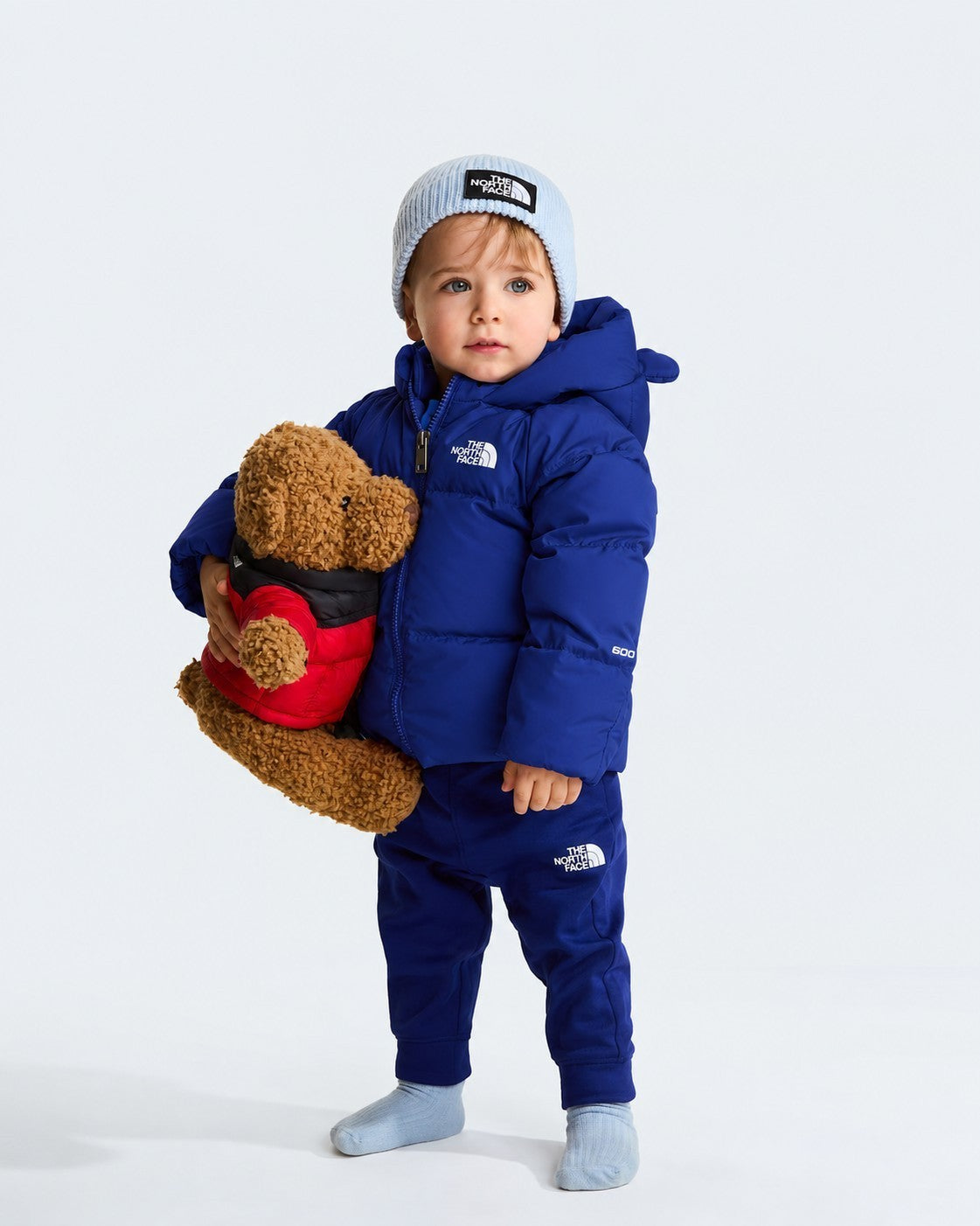 Bambino che indossa giacca in piumino blu THE NORTH FACE con fodera in pile e berretto Follower SRL